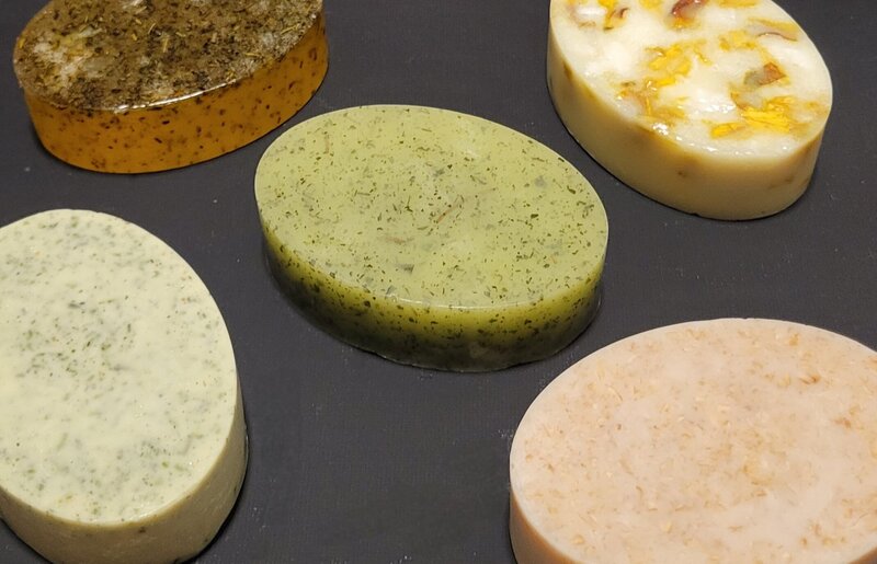 Display of all of Berry and Balm handmade soap laying on a black cloth, showing off the natural ingredients 