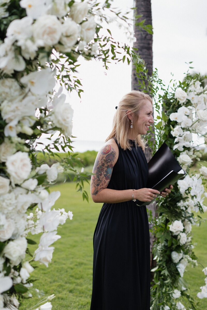 ashlee felton, an officiant standing at the beginning of the ceremony, looking out and smiling into the crowd at a wedding at the four seasons in oahu