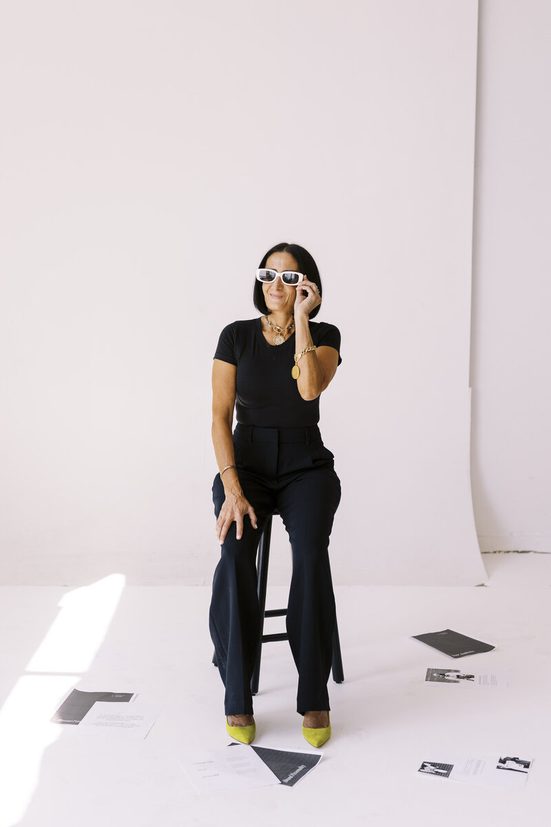 Tarah Baiman sitting on stool with paper scattered on floor