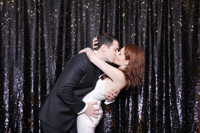 holywood couple kissing front of ths black sparkly backdrop