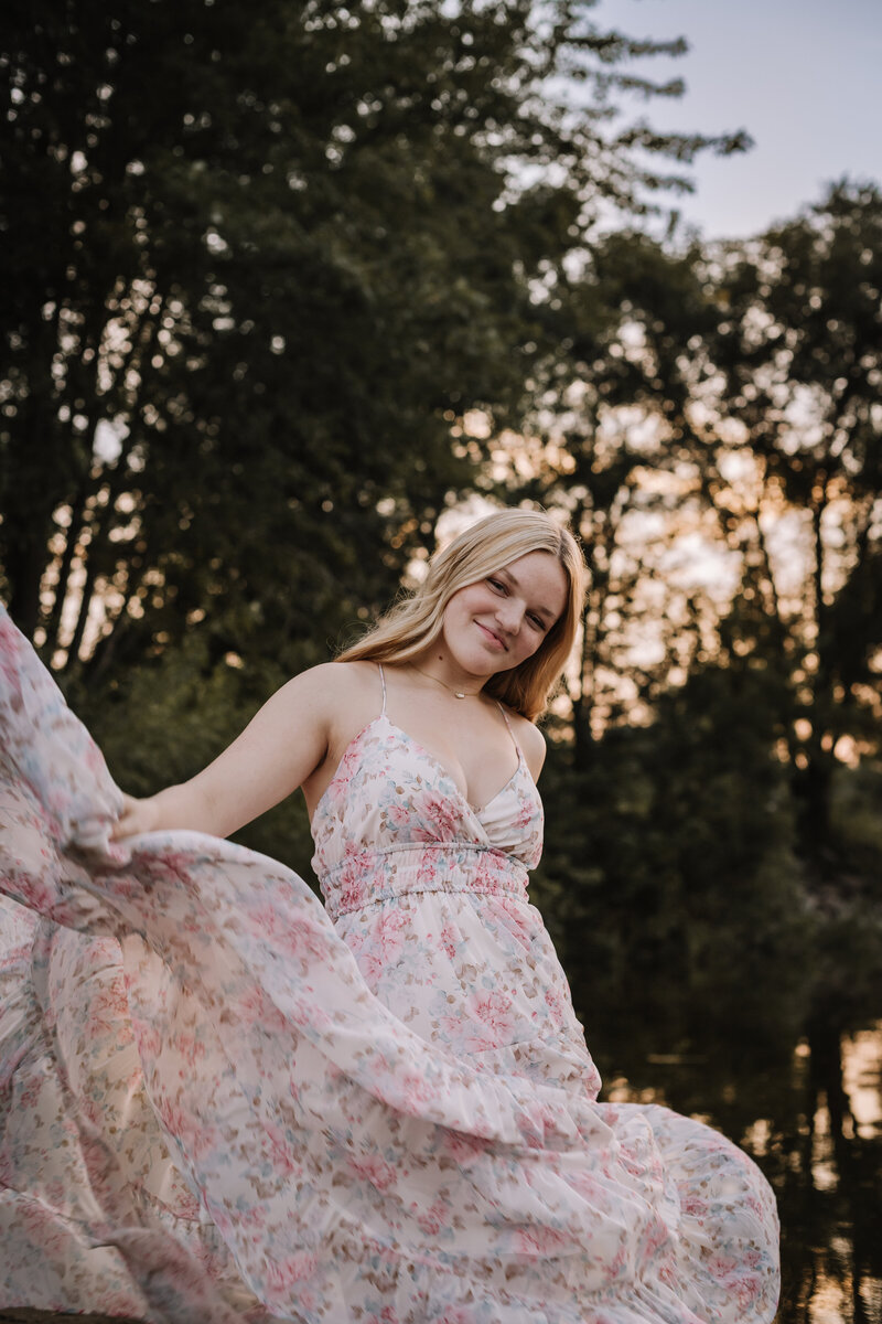 A young women is a flowing dress under an iowa sunset