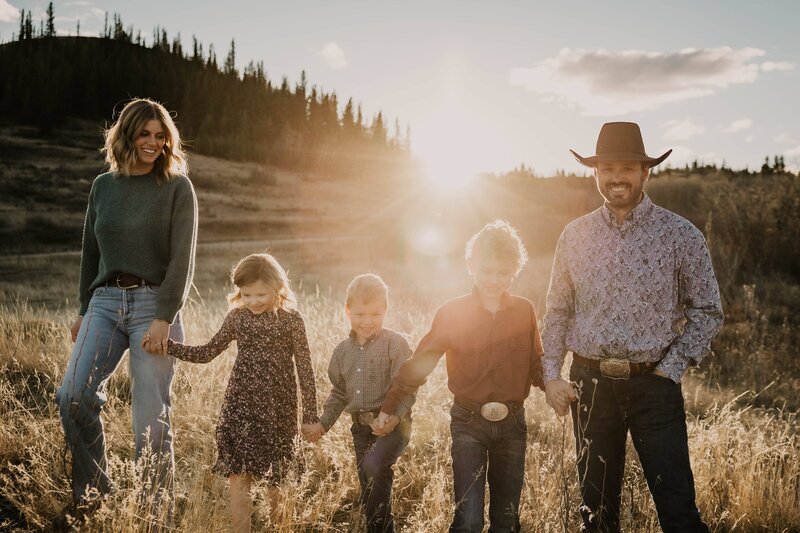 Family photograph of mom, dad, and kids in a pasture at sunset in Saskatchewan 