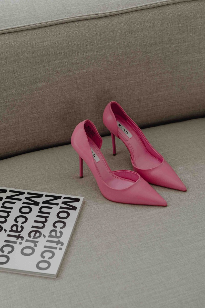 Natalie Bernacchi sitting on a bed with a laptop, smiling off to the side in a bright, cozy space.