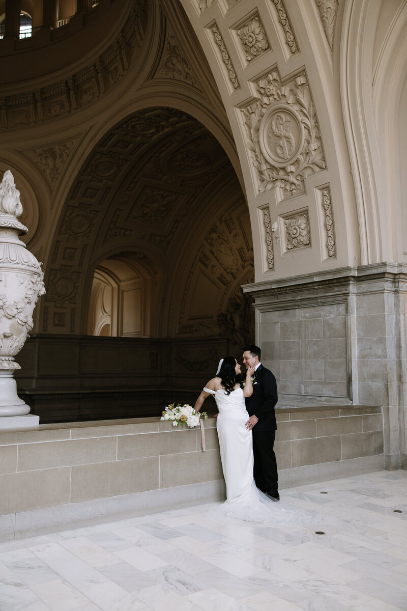 Eloping couple embracing during private moment at San Francisco City Hall in Northern California