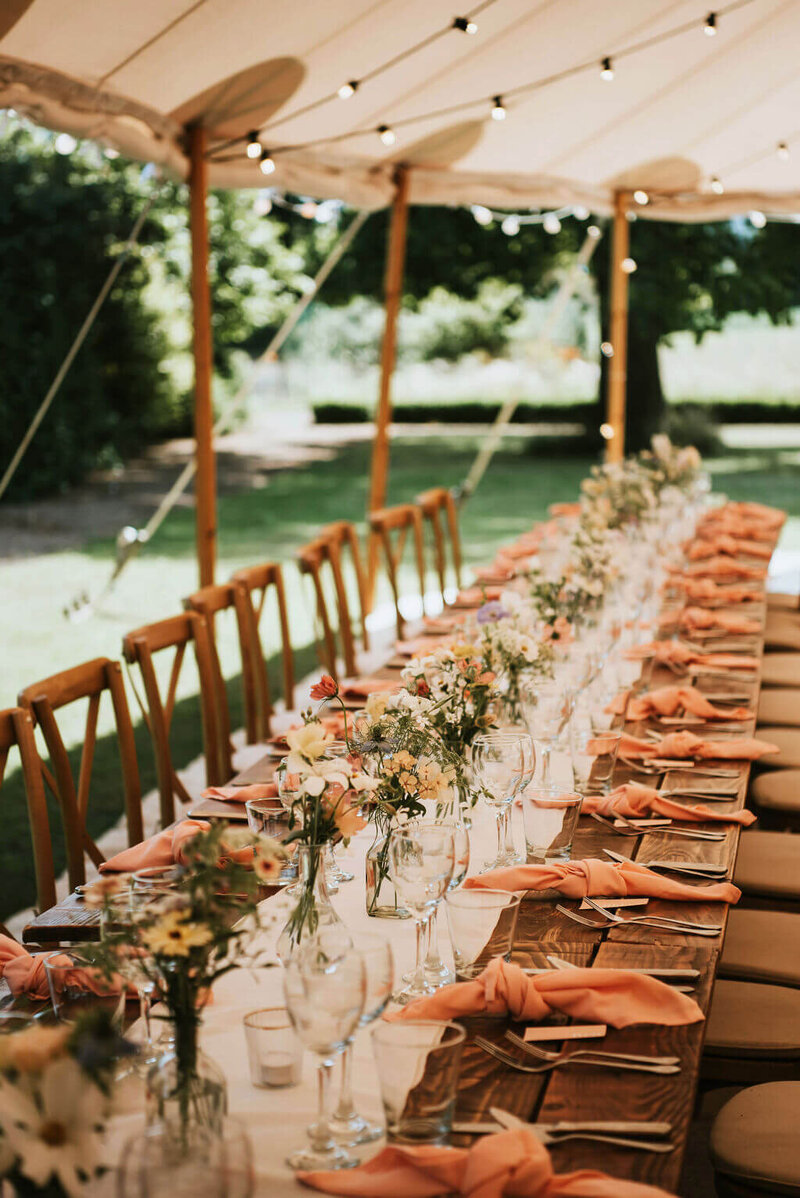 Long tables in the marquee at Broadfield Court dressed with bud vases of flowers