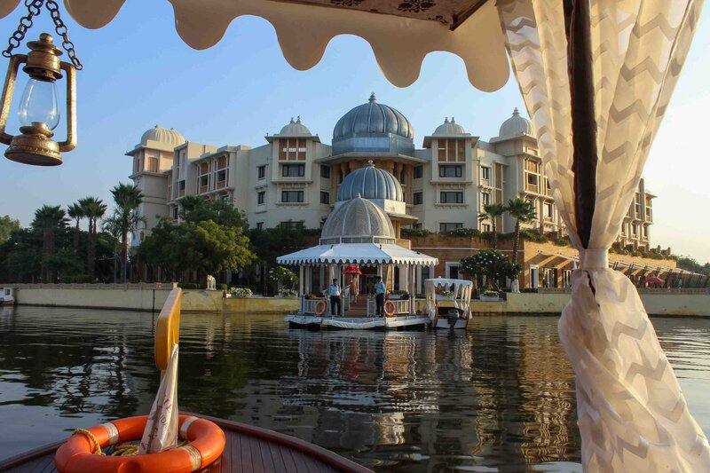 View from a wooden boat with curtained canopy and lantern approaching the domed water taxi dock at the Leela Palace Udaipur, India ©Stephanie Dosch | theViatrix Luxury Travel