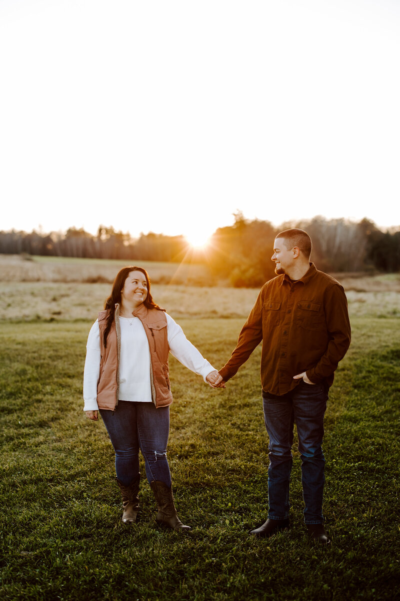 Engagement session during sunset in Hollis, New Hampshire couple holds hands and looks at each other