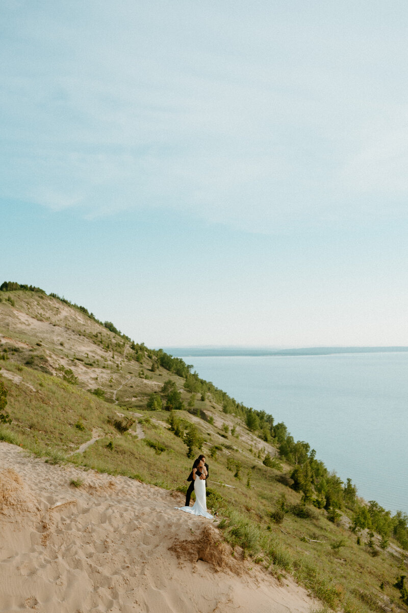 Couple on Empire bluff holding each other looking out at lake michigan