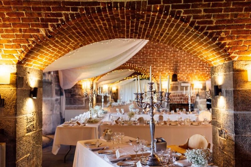 A beautiful wedding breakfast set up with white flowers, candelabras and long tables