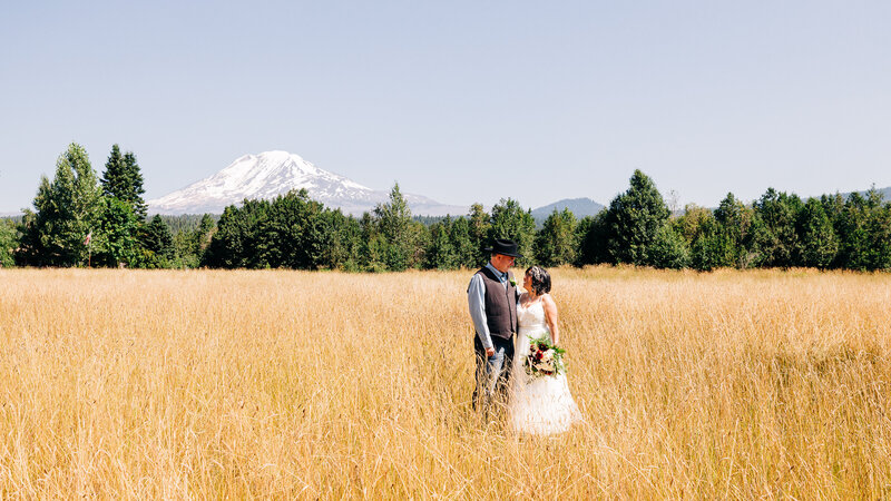 Bride and Groom in field with mountain backdrop