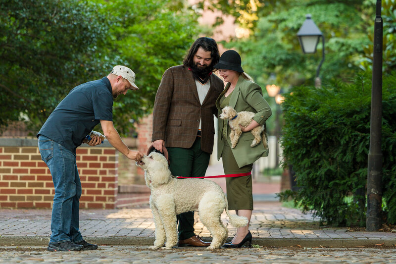 Travis Stitt engaging with a dog to capture its attention during a 101 Dalmatians-inspired engagement session, creating a fun and playful moment that highlights the couple’s love for their pets.