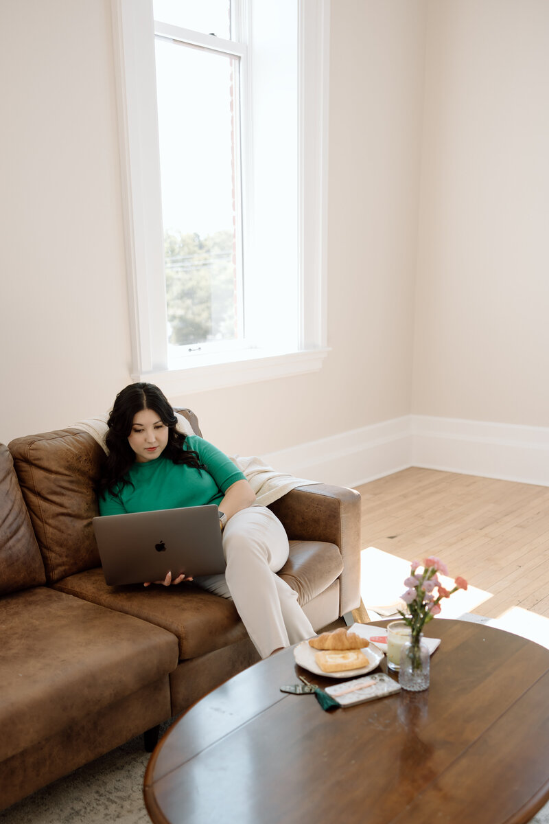 Shanté Gorman, founder of Sugarpunch Marketing®, a content and social media agency, sitting on a couch with a laptop, smiling.