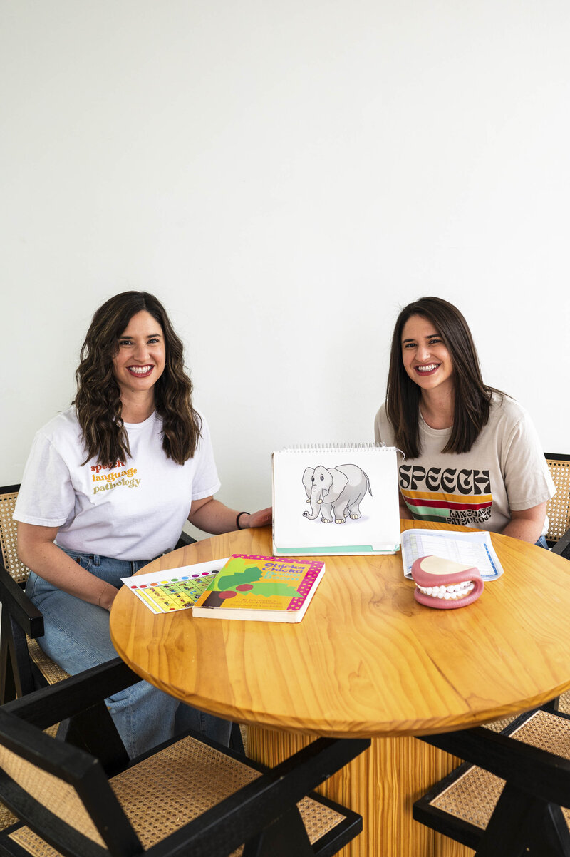 Victoria and Christina sitting at table with speech and language books