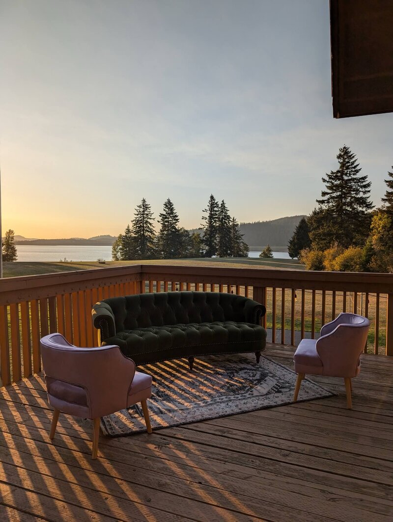Sofa and lounge chairs on a deck at sunset, representing affordable and luxury event rentals by Birdie June.