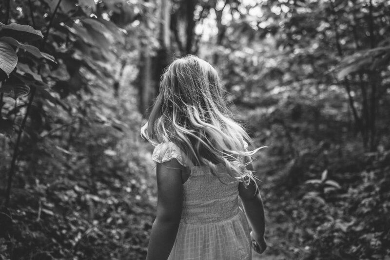 Emotive black and white portrait of a young girl walking down a path away from the camera in Farmington, Missouri. 