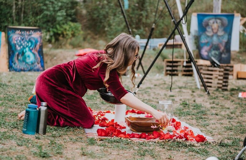Shae is preparing for an outdoor ceremony by laying down red rose petals