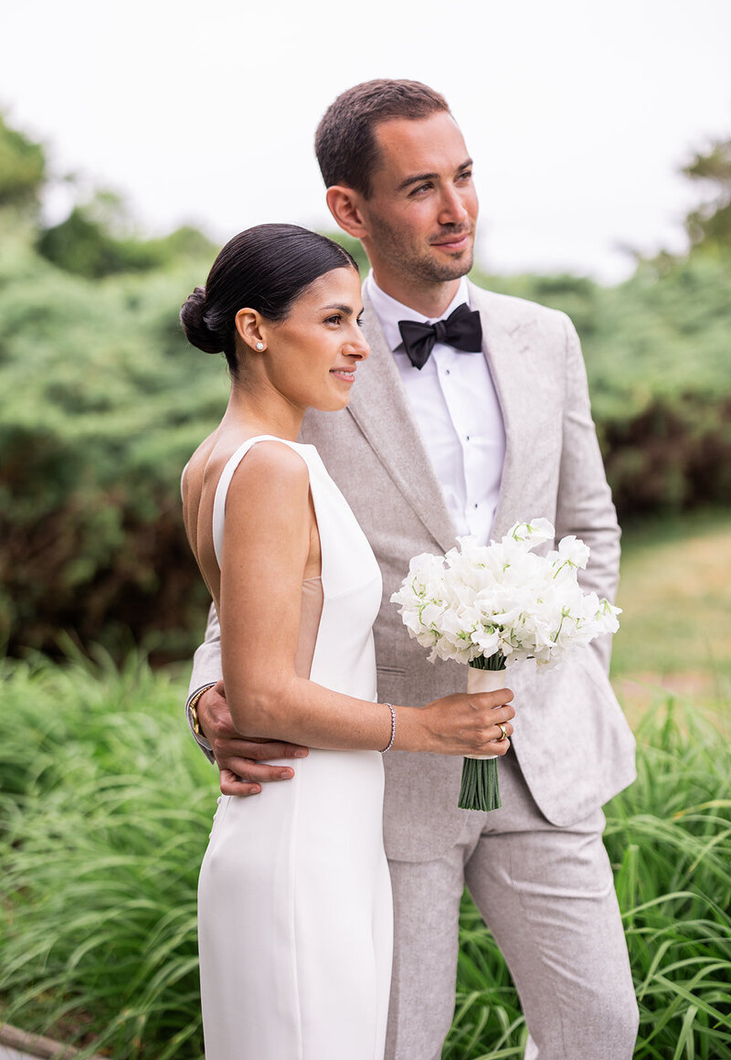 A wedding couple, groom dressed in off white suit with black bow tie