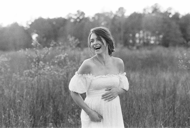 Mother laughs and holds belly during her maternity session by Nashville Photographer Grace Paul