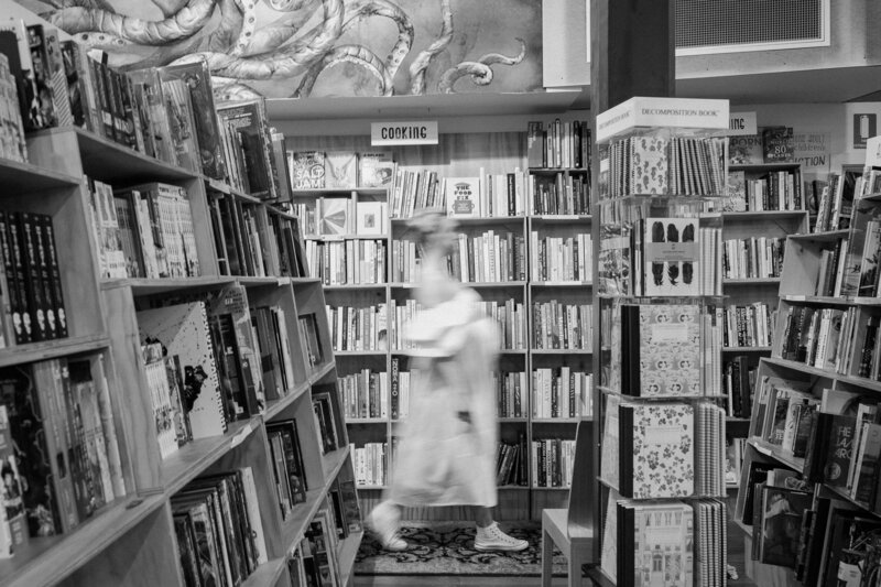 Indoor maternity photo session. Pregnant mother walking through bookstore.