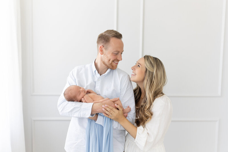 parents smiling while holding their newborn