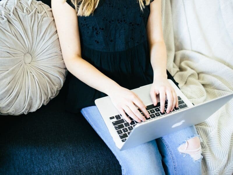 woman sitting on couch with a laptop learning about blogging tips