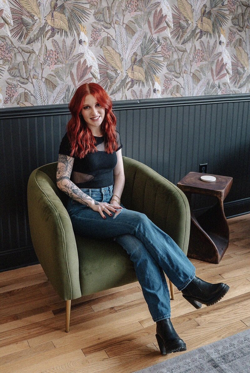 Beauty by Bayley - Woman with red har and tattoos sitting in a chair