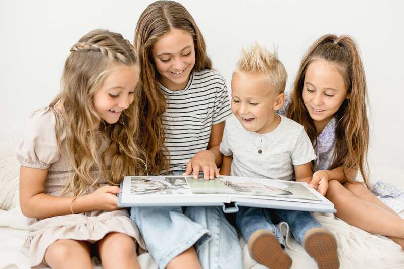 four happy siblings looking at their family photos in an heirloom signature album