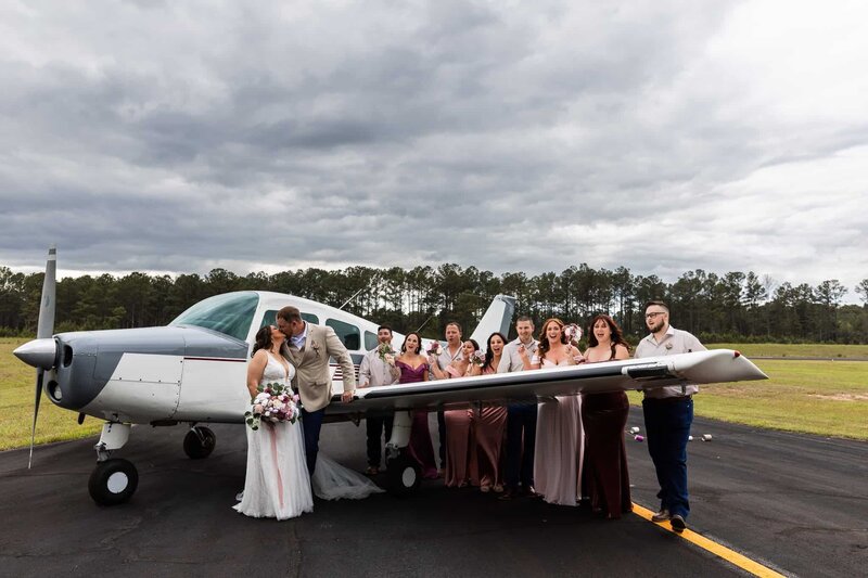 A bride and groom pose in front of a private plane with their entire wedding party lined along the wing—cheering, laughing, and living the moment. This bold, windswept image speaks to the couple's adventurous spirit and the kind of storytelling adventure wedding photography you’d expect from a creative team rooted in Pennsylvania but open to the world.