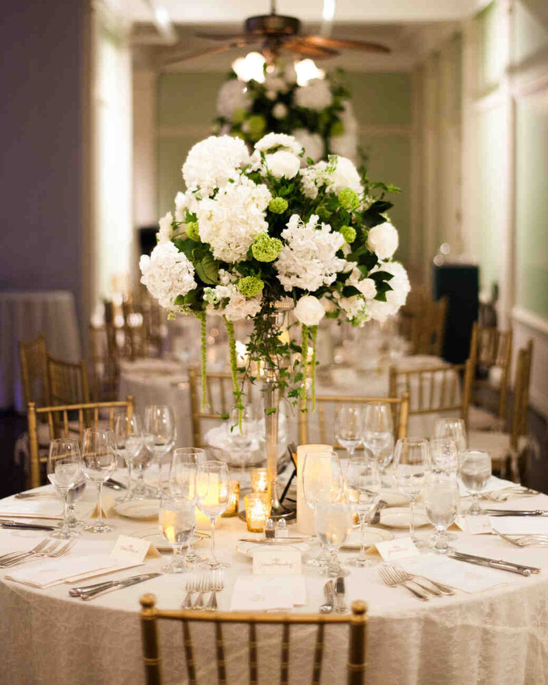 White and Green flower bouquet on a table with a full place setting