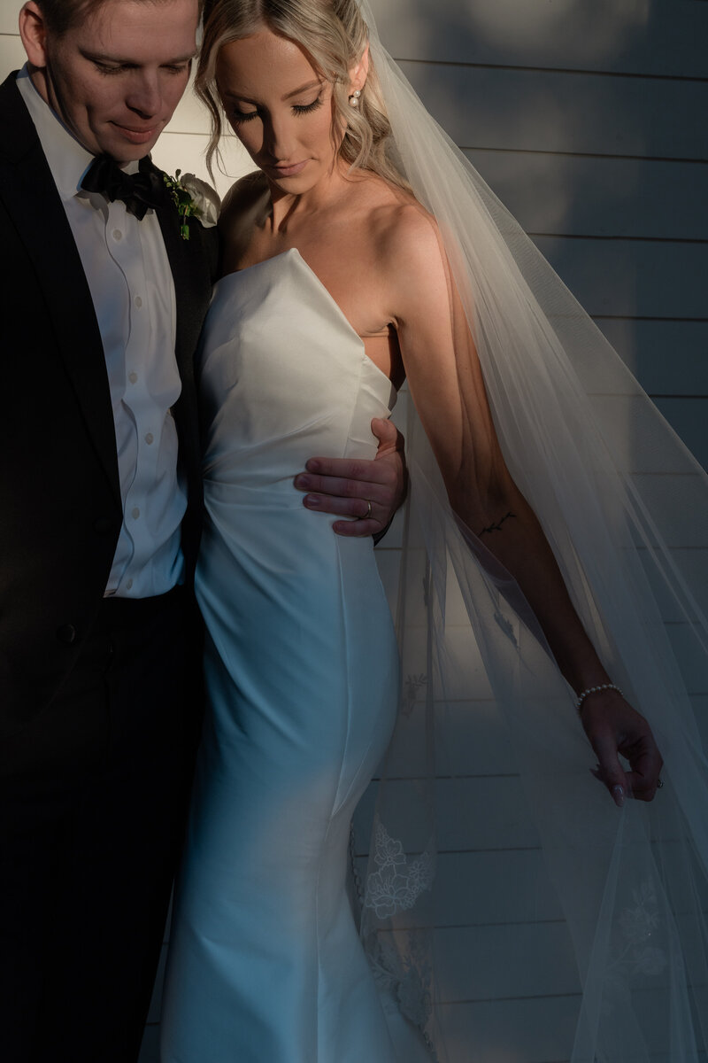 Newlyweds sharing a quiet moment on the beach in Nantucket, with soft coastal light and ocean in the background.