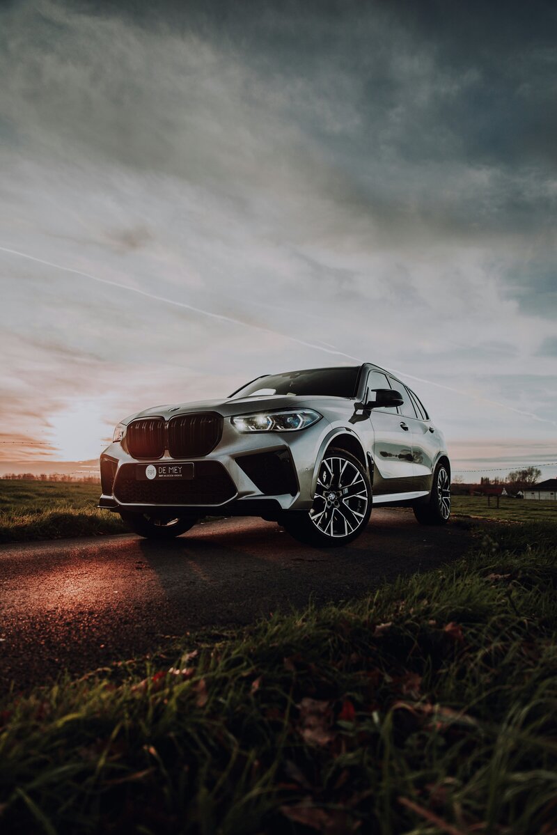 shiny, new black BMW car parked with a sunset behind
