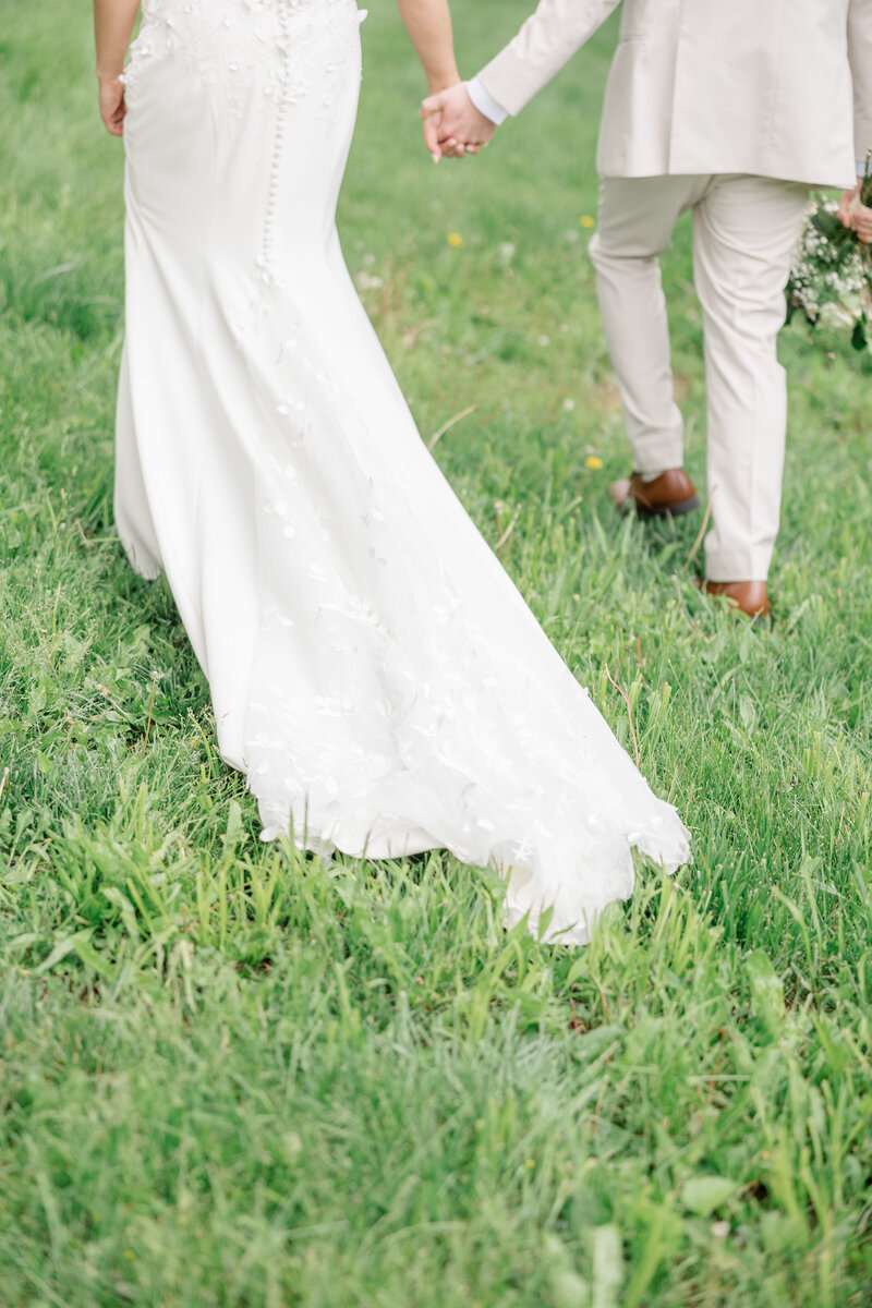 Close up of Brides dress on the ground and bride and groom walk.