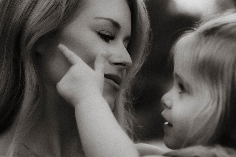 Mother holding daughter while she touches the moms face.