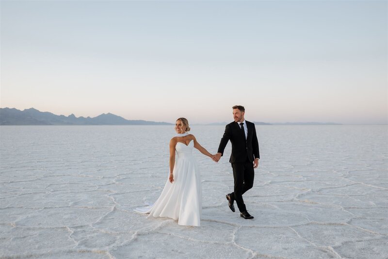 couple holding hands in their wedding attire on the salt flats.