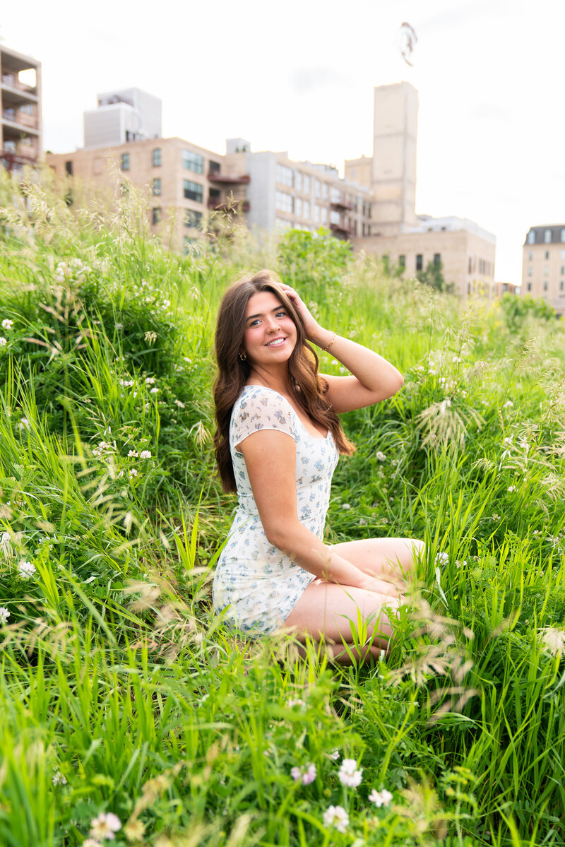 High school girl sits in a wildflower field for her senior photos