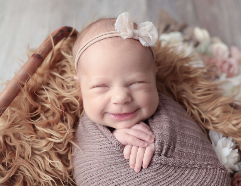 Smiling newborn girl posed  in our Rochester NY studio.