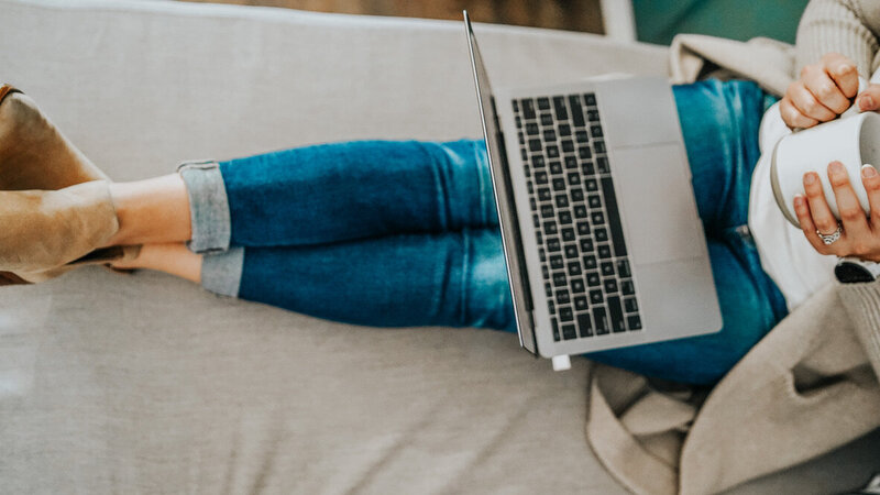 Katelin holding a coffee mug with a computer in her lap