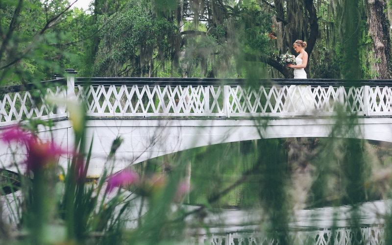  A bride walks across a bridge at a plantation in Charleston, South Carolina. 