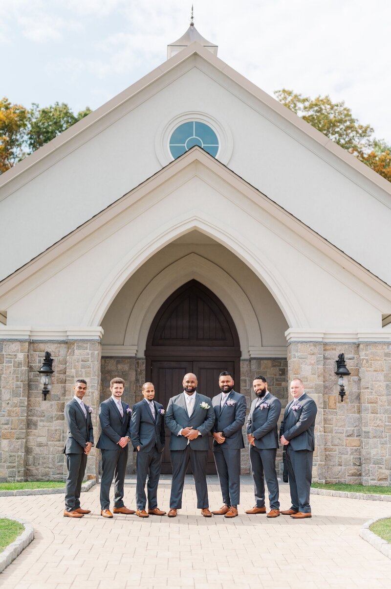 Groomsmen pose in front of the Chapel at Aria for a forma photo. 