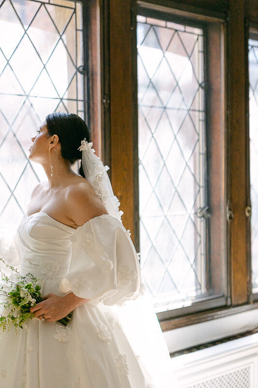 A bride looking outside at the window of Club Atwater, top wedding venue in Montreal.