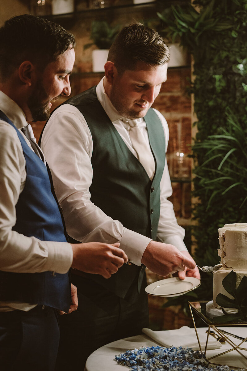 gay couple cutting wedding cake