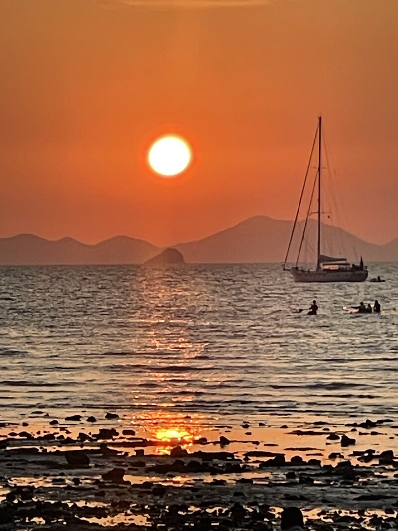 Photo of a very beautiful orange sunset over the sea with a sailing boat