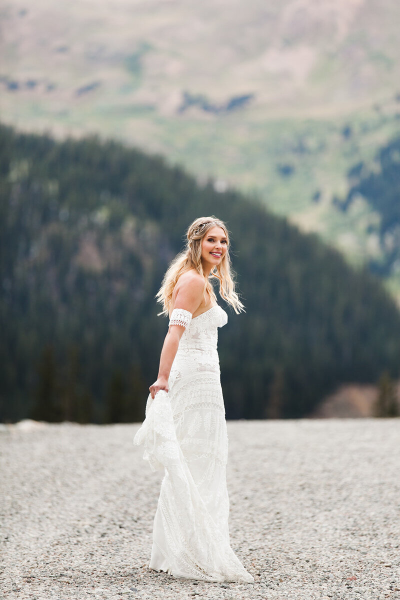 bride walks on a dirt road by mountains at her keystone, colorado wedding