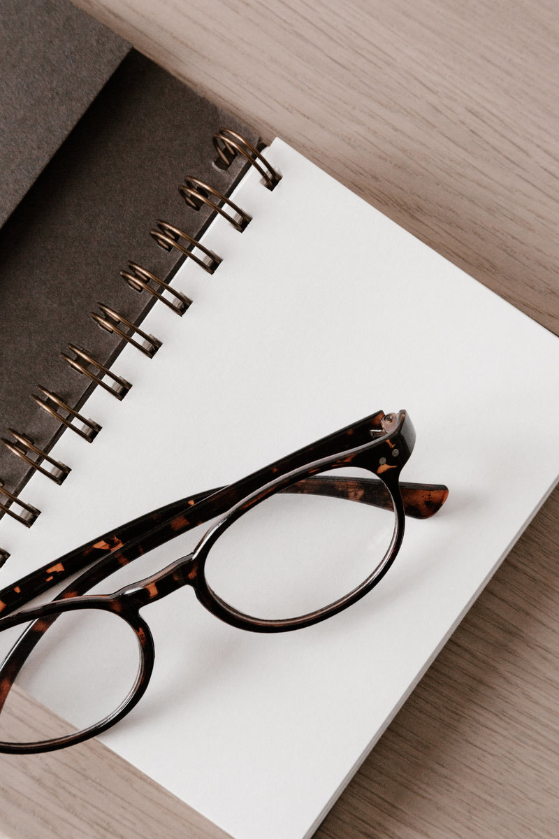 Reading glasses sitting on blank notebook on a desk