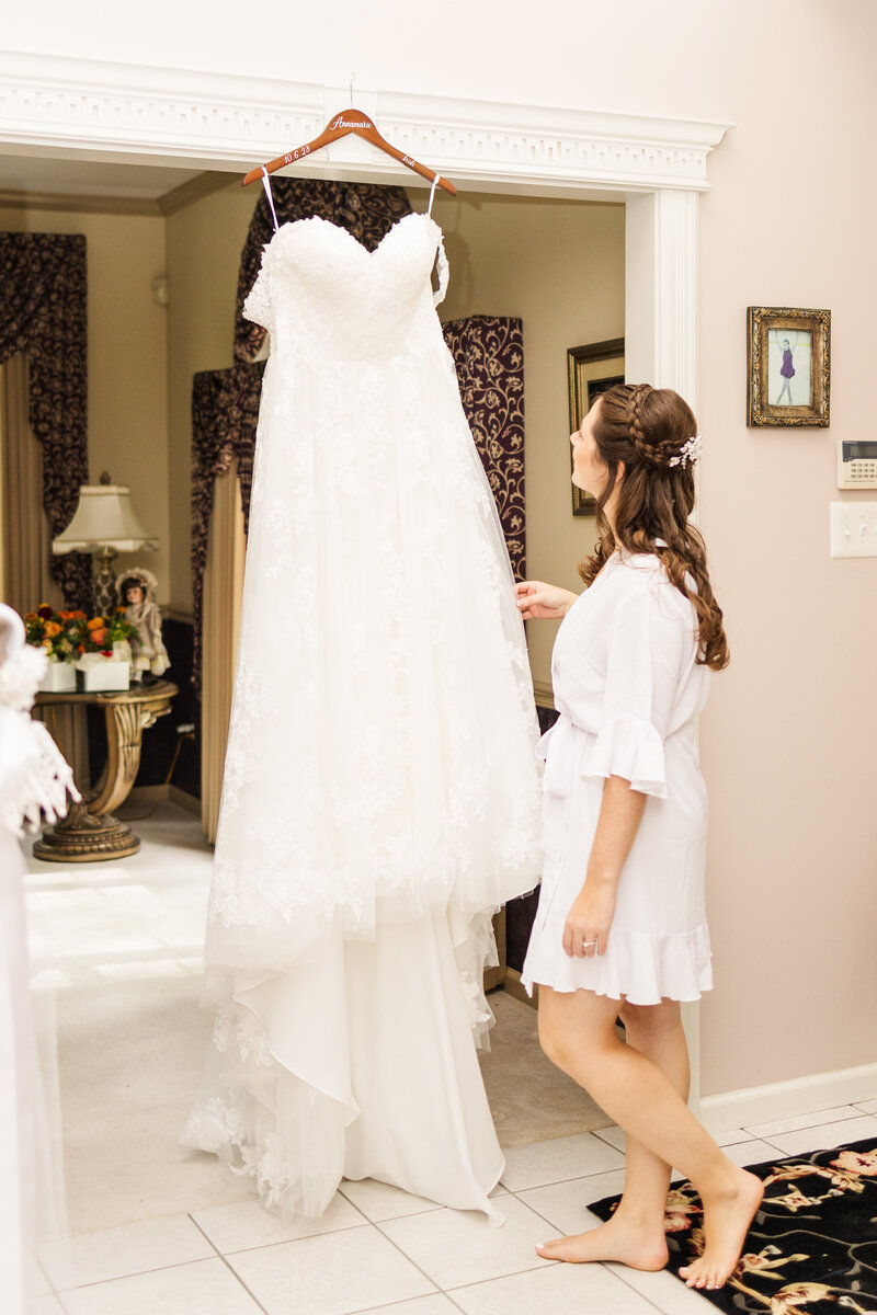 A bride admires her hanging dress in a luxurious getting ready room