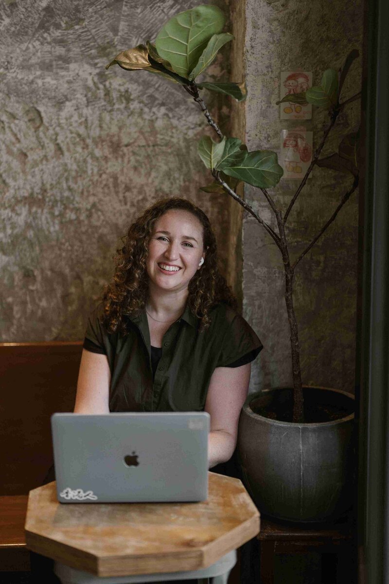 Christy Walowit, owner of Eat Beyond Labels, sitting at a table with a laptop.