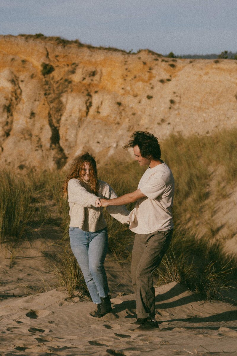 A couple holding hands and spinning on a beach 