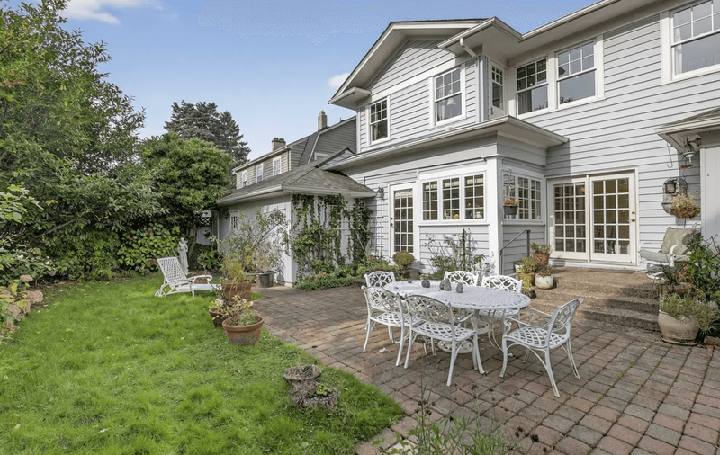 The back of a colonial house featuring a patio white white iron table and chairs.