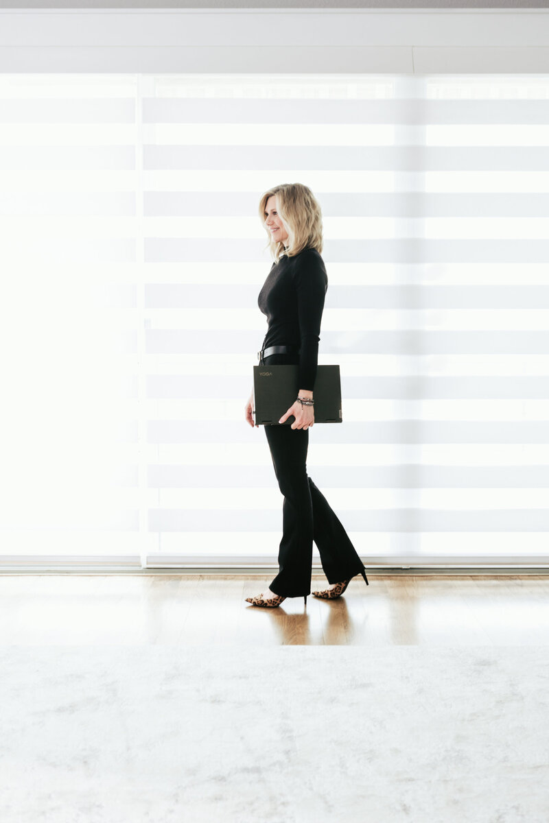 Kristin Tibbs walking in a bright, modern space—representing professionalism and clarity in luxury real estate services.