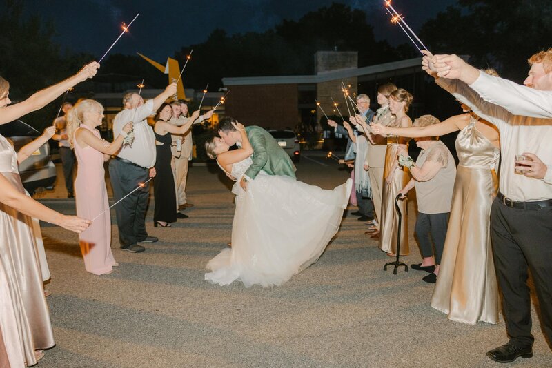 Bride and groom dip and kiss during sparkler exit